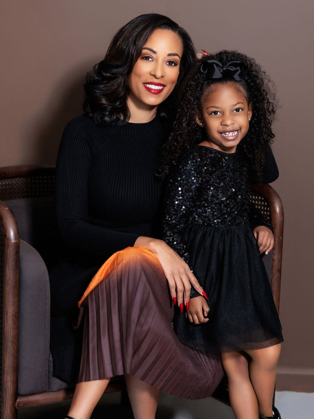 Courtney seated with her daughter Cristina, both in black, studio portrait