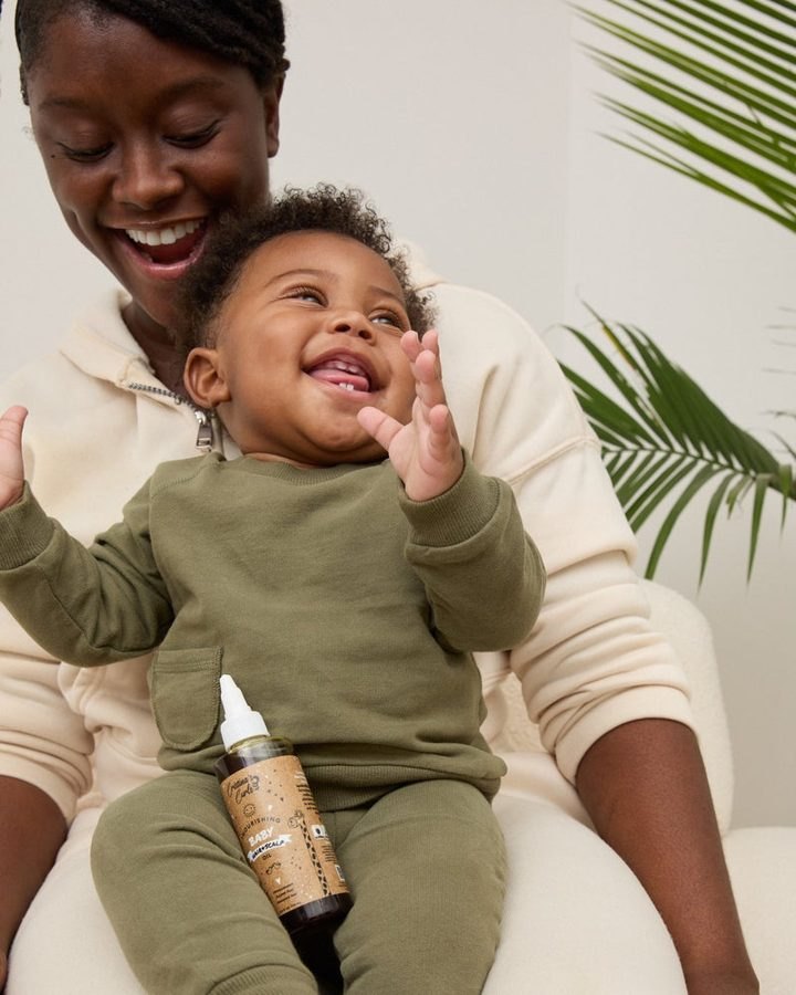 A laughing parent with her smiling baby on her lap