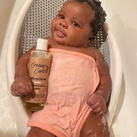 A baby in a bath seat with the baby shampoo