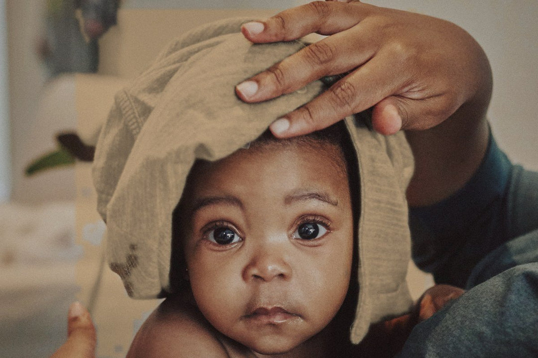 A parent presses a soft tan towel on a baby's head after the bath