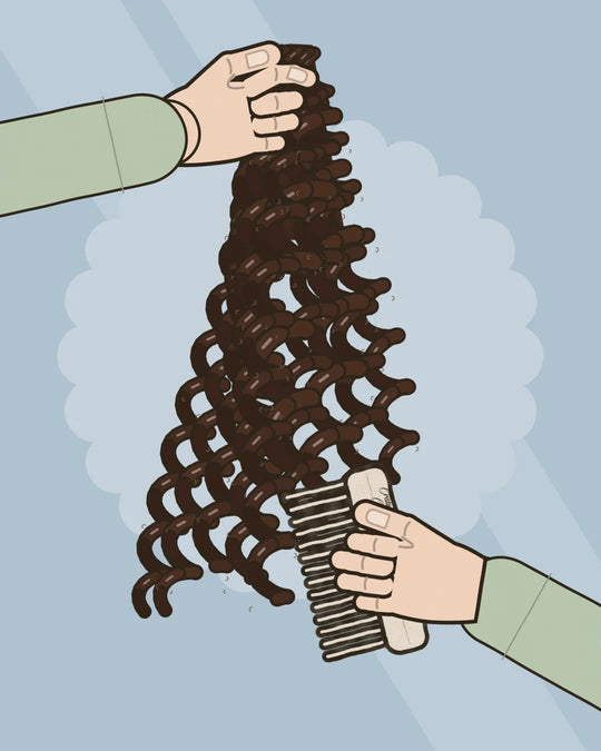 Courtney crouches beside her toddler on a low stool, holding one curly section up with one hand and combing through its ends below with a wide-tooth comb in the other, the Nourish + Grow Conditioning Detangler beside them.
